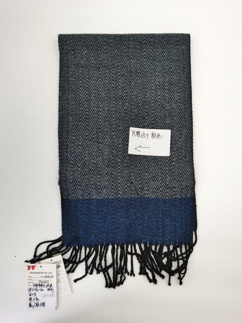 Grey and blue herringbone woven scarf with color block design and black fringe trim, laid flat on white background