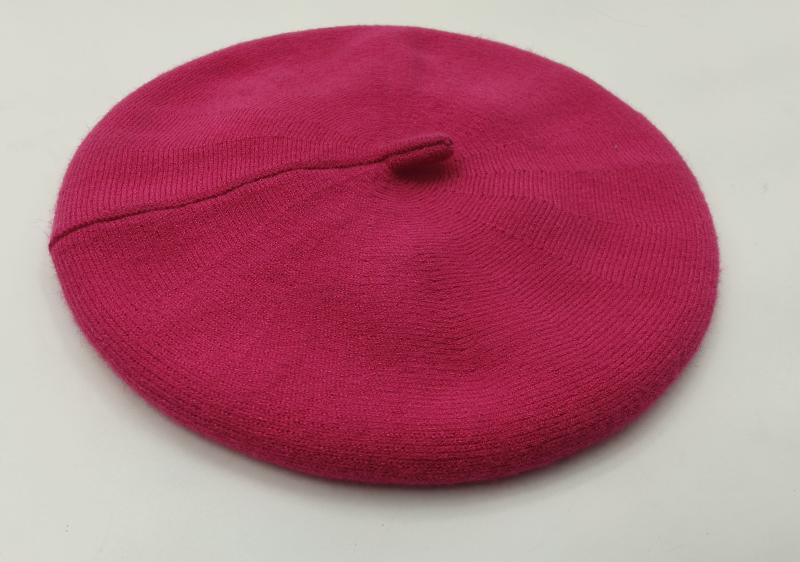 Flat lay of a hot pink fine knit wool beret with ribbed brim and center stem on white background