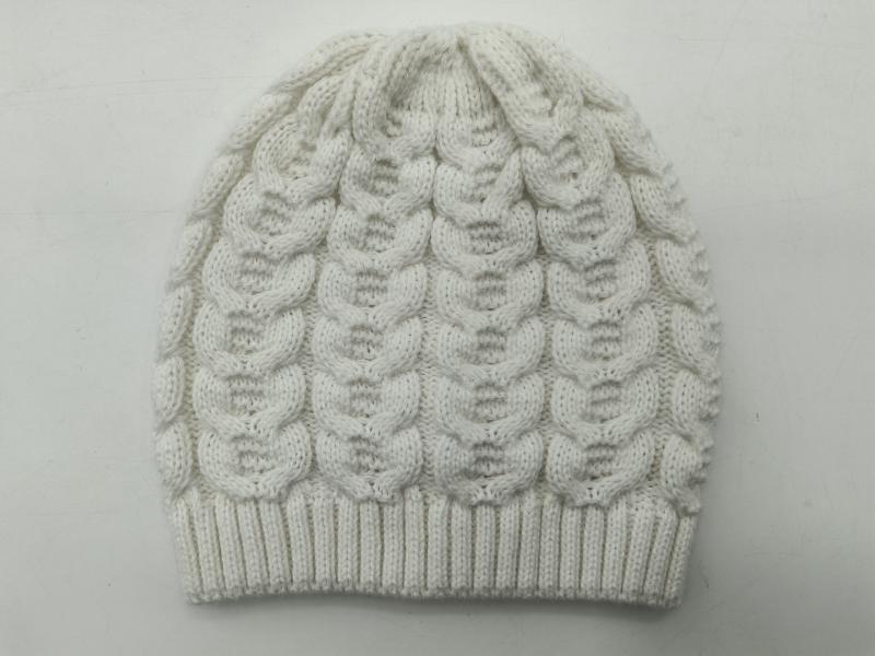 White cable knit winter beanie hat with bubble pattern texture and ribbed cuff, laid flat on light background
