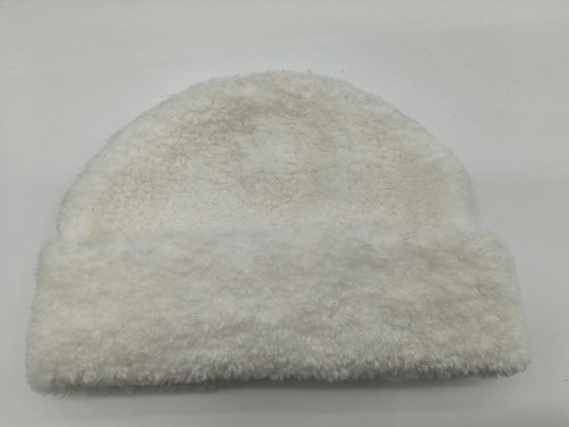 White cream sherpa fleece beanie hat with curly teddy texture, laid flat on white background, cozy winter accessory