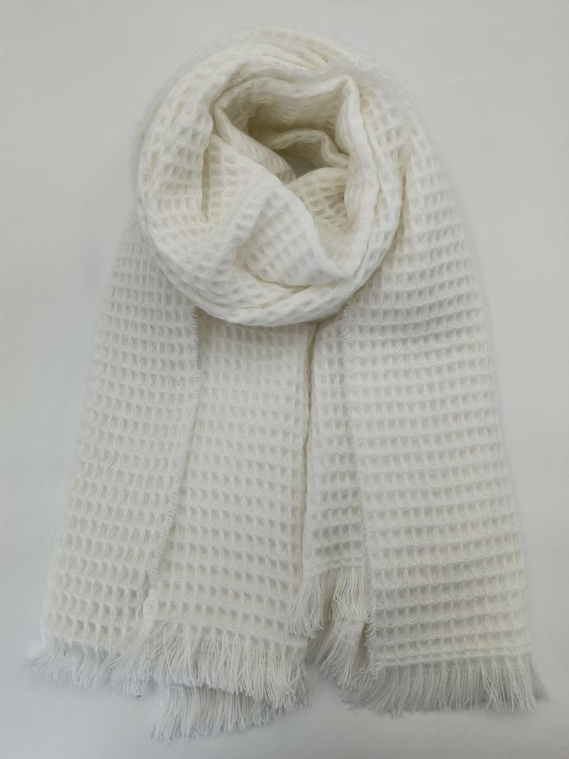 Ivory white waffle knit scarf with fringe ends, rolled and laid flat on white background showing textured grid pattern