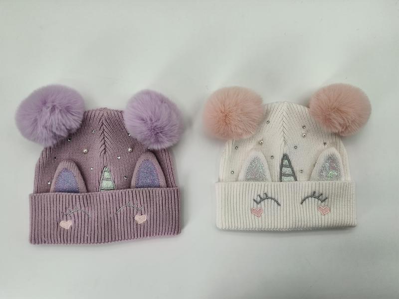 Two unicorn knit beanies in lavender and cream with fluffy double pompoms, glitter horn ears, lash embroidery, and rhinestone details