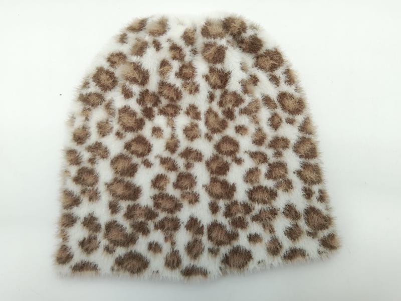 Soft white faux fur beanie hat with brown leopard print spots laid flat on white background