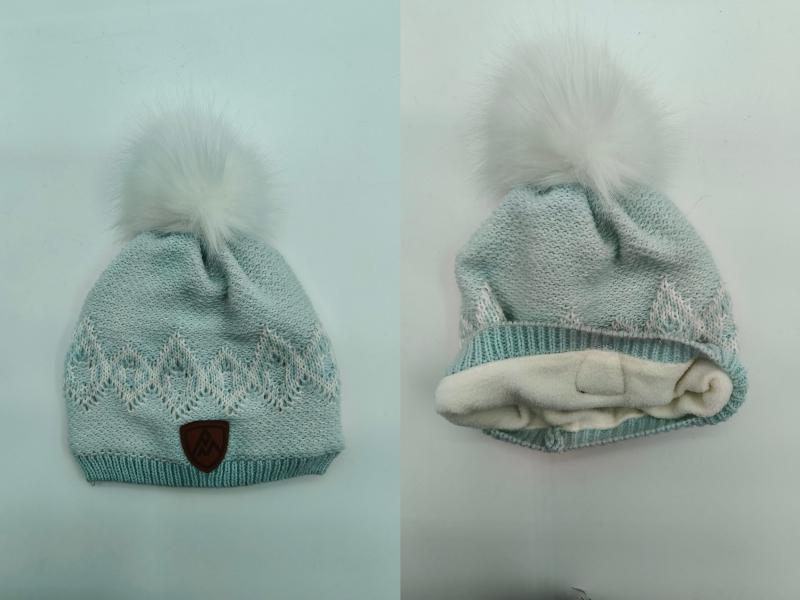 Mint green knit winter beanie with white faux fur pompom, jacquard pattern, fleece lining, and leather logo patch
