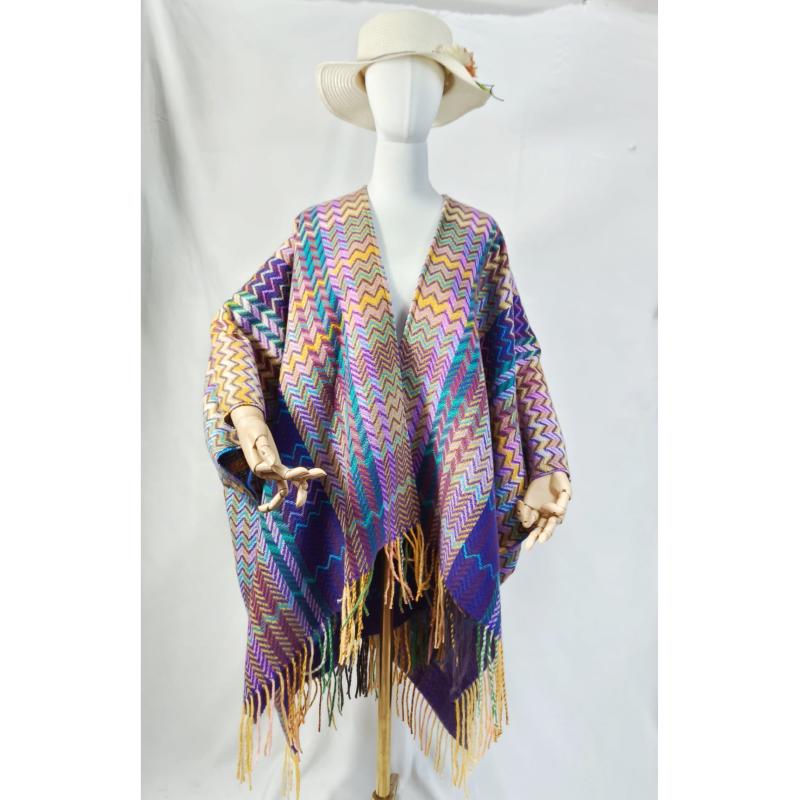 Mannequin wearing a multicolor chevron zigzag woven poncho wrap with long fringe trim and wide-brim hat