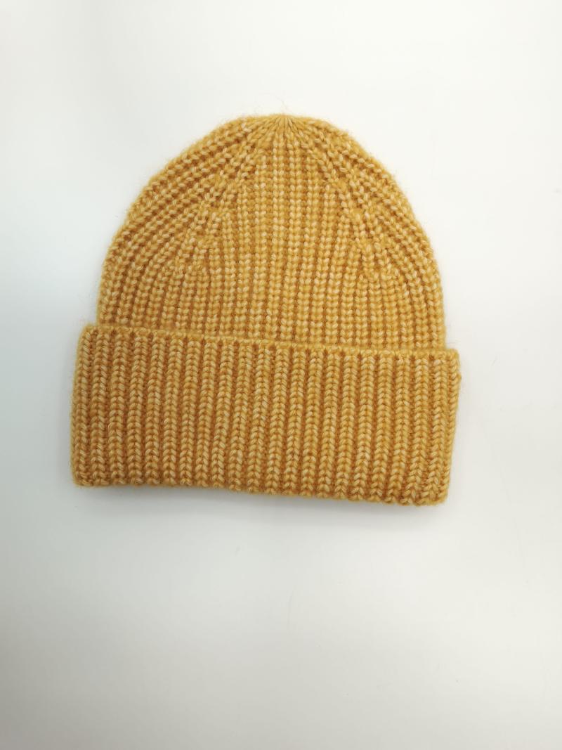 Mustard yellow chunky ribbed knit winter beanie hat with folded cuff laid flat on white background
