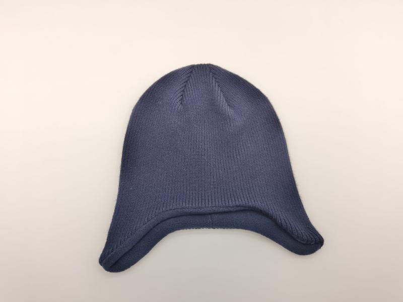 Navy blue ribbed knit winter beanie hat with ear flaps laid flat on white background