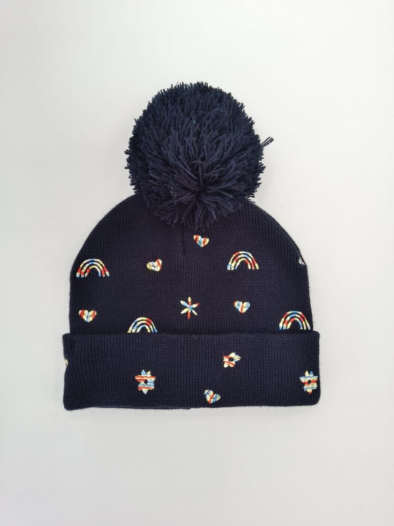 Navy blue ribbed knit bobble hat with large pom-pom and colorful embroidered rainbow, heart, and star motifs